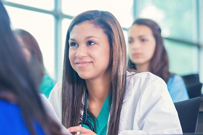 Young nursing student listening to professor in medical class